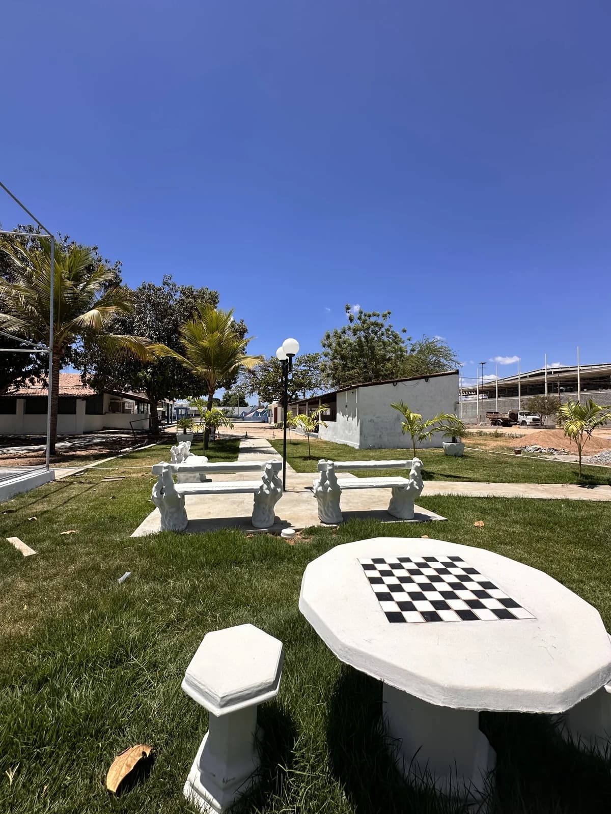 Área de convivência com jardim, bancos e mesas de jogos ao ar livre